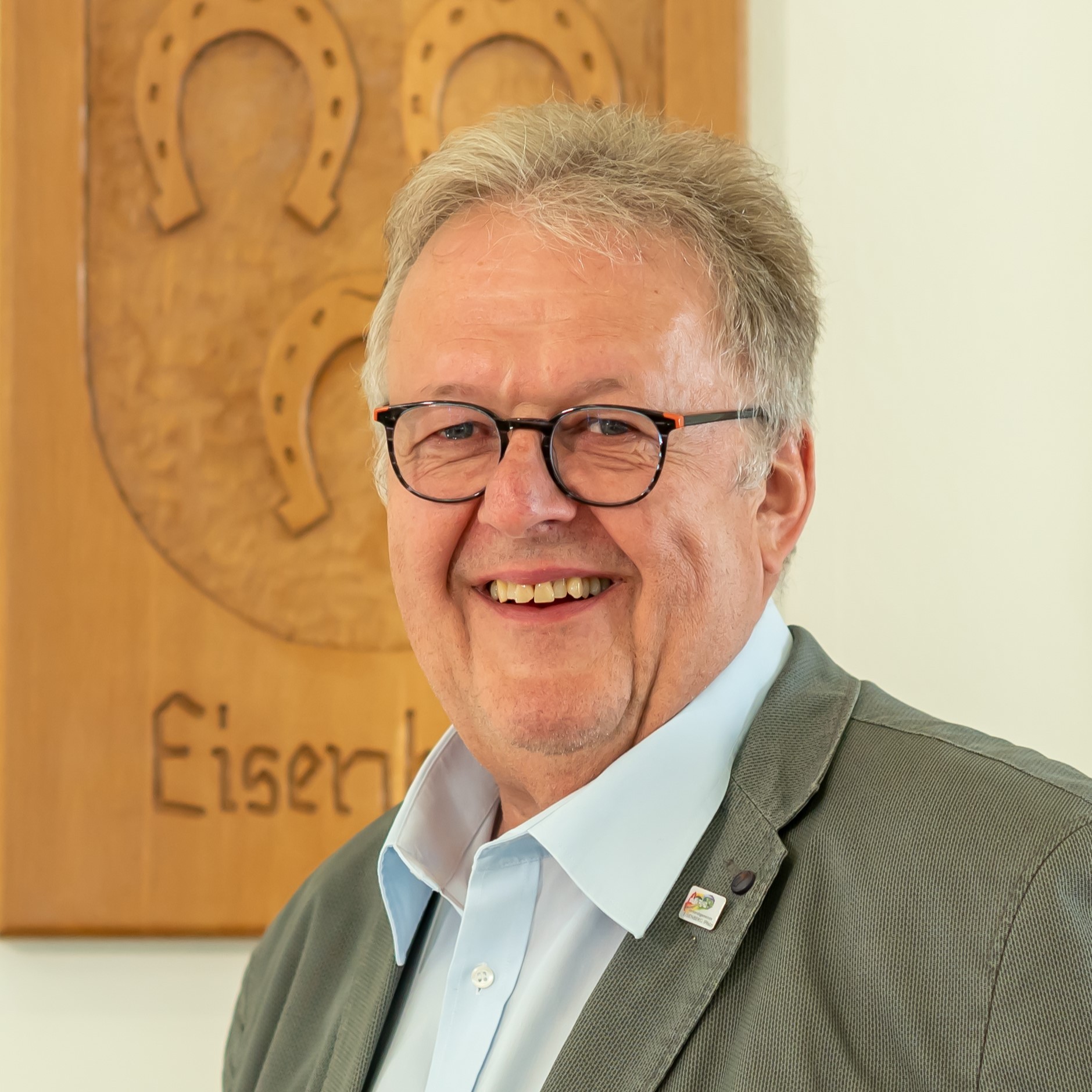 Porträt von Herrn Frey mit einem Wappen im Hintergrund