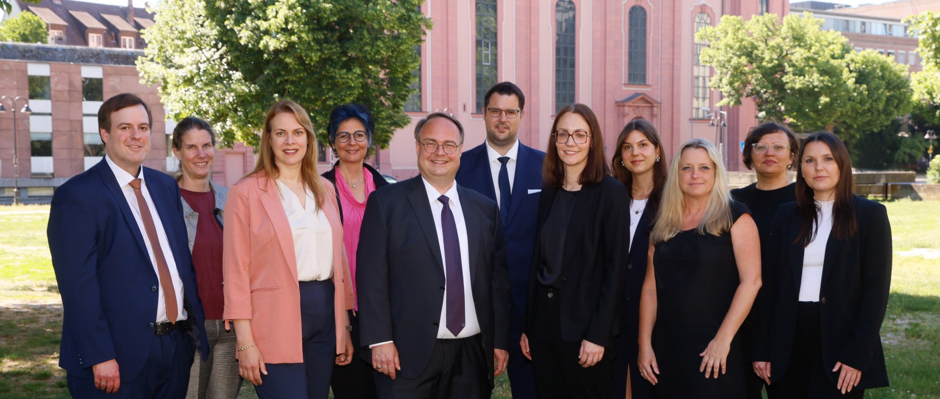 Gruppenbild der Mitarbeiter mit grün im Hintergrund